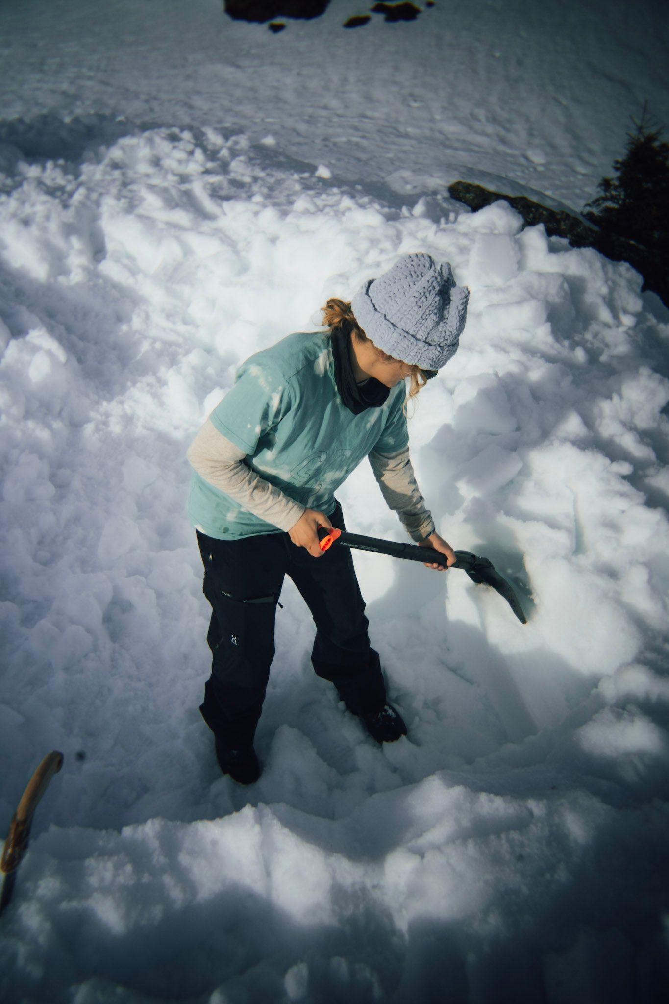 Freeriderin gräbt bei einer Lawinenübung mit der Schaufel im Schnee